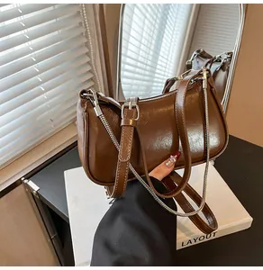 Détail du sac à bandoulière en cuir ciré marron avec chaîne argentée et sangle réglable