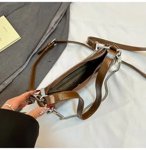 Vue intérieure du sac en cuir marron avec doublure rayée et détail de chaîne argent