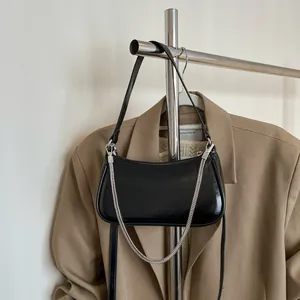Sac baguette chic en cuir ciré noir avec chaîne argentée et bandoulière sur cintre