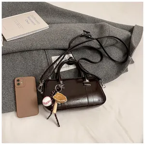Détail d'un sac Boston marron en cuir ciré avec pendentif sport et bandoulière chic