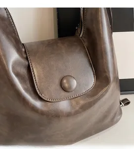 Close-up of vintage dark brown tote bag showing textured leather material and metal buckle