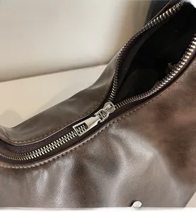 Detail shot of a smooth silver metal zipper on a dark brown vintage leather tote bag