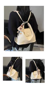 Cream leather tote bag detail with lion plush charm and multi-way shoulder straps