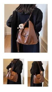 Detail of vintage brown leather hobo bag with round buckle and colorful plush charm