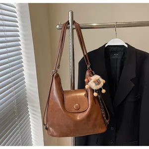 Detail view of brown vintage tote bag with a round buckle and cute plush lion charm pendant