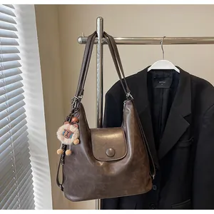 Detail of dark brown faux leather tote bag with a cute plush lion charm on metal rack