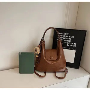 Detailed view of brown faux leather backpack with magnetic flap and cute plush charm detail