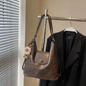 Brown vintage faux leather tote bag with lion charm and convertible straps on a hanger