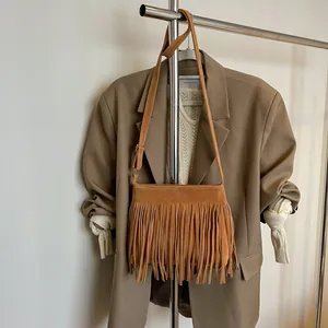 Détail d'un sac bohème à franges en daim marron suspendu à côté d'une veste