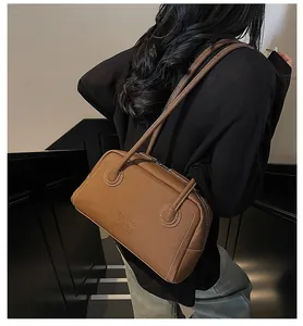 Détail du sac en cuir caramel avec coutures contrastées blanches et texte embossé