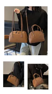 Détail d'un ensemble de sacs en cuir marron mat avec surpiqûres blanches et logo embossé