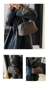 Détail d'un sac à main en cuir marron foncé montrant les coutures et la texture