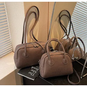 Détail du sac à main en cuir marron foncé avec surpiqûres blanches et zip métallique