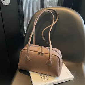 Sac Boston vintage marron avec doubles bandoulières et logo embossé sur le cuir