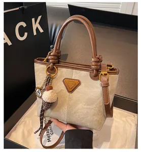 Detail of canvas tote bag with leather trim, metal logo, and plush ice cream charm decoration