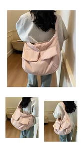 Detail of pink canvas crossbody bag featuring large front flap pockets and wide strap