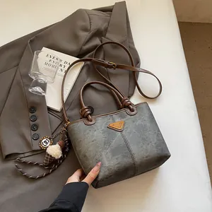 Vintage tote bag with brown handles and gray body shown on a brown blazer with decor