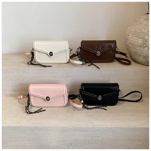 Collection of shiny leather crossbody bags in four colors on stone steps