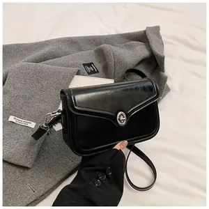 Close-up of black glossy leather crossbody bag with metallic silver twist-lock closure