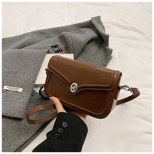 Detail of a brown leather retro square bag with a silver swivel lock and fine stitching