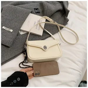 Detail of a beige leather mini square bag with silver twist lock on a wool coat