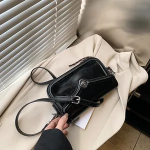 Chic black glossy leather crossbody bag with silver buckle and stylish pleated texture