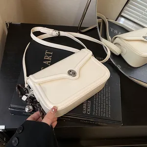 Elegant cream-colored small square shoulder bag with silver rotating lock and charm