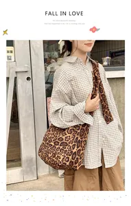 Detail of a large leopard print canvas crossbody hobo bag with a wide shoulder strap