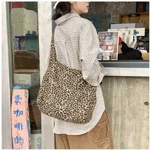 Macro shot of large leopard print canvas tote bag with wide strap in a cafe setting