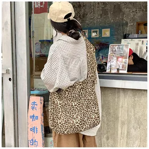 Detailed side view of a large leopard print canvas crossbody bag on model at a cafe