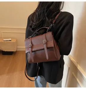 Brown vintage messenger backpack with top handle and buckle straps shown on model