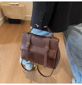 Detail of vintage brown leather satchel featuring dual buckle straps and silver hardware