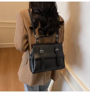 Rear view of a black vintage leather backpack worn with a brown blazer and blue jeans