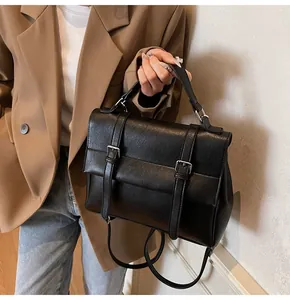 Classic black leather messenger bag featuring vintage buckle straps and top handle detail