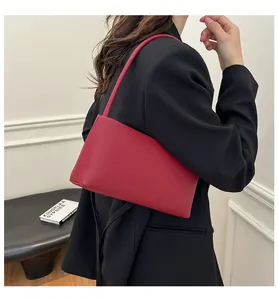 Deep red minimalist baguette shoulder bag shown on model in a modern interior setting