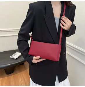 Close-up of minimalist red rectangular shoulder bag on a model in a black blazer