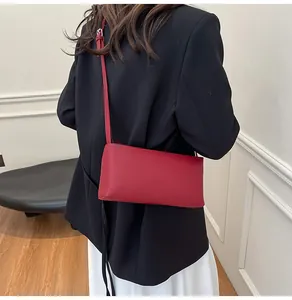 Detailed view of red baguette bag showing matte leather texture and adjustable shoulder strap