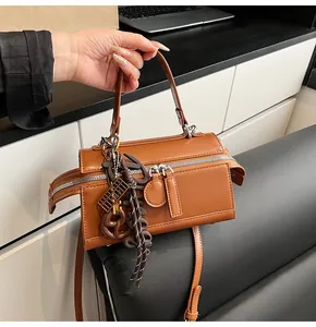 Detailed view of brown leather handbag featuring dual zippers and stylish bag charms
