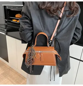 Detail of a chic dark brown PU leather crossbody bag with dual zippers and decorative charm