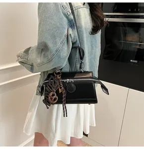 Detail of black rectangular crossbody bag with silver double zippers and decorative charms