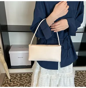 Minimalist cream white baguette shoulder bag shown on model with sleek faux leather finish