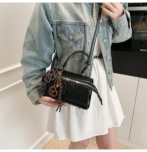 Detail of black matte crossbody pillow bag with silver zippers and decorative charms