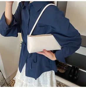 Close-up of minimalist cream white baguette bag with smooth faux leather finish