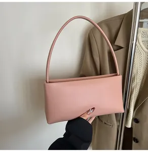 Close-up of minimalist pink baguette bag held by a person in a stylish suit