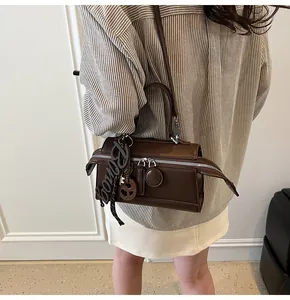 Close-up of deep brown leather crossbody bag featuring silver double zippers and Bongo charms