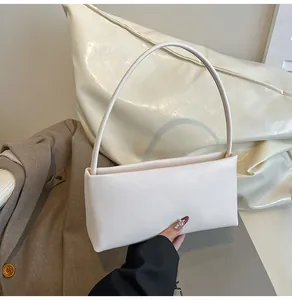 Detail of minimalist cream leather baguette bag styled on a blazer for a chic look