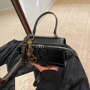 Fashionable black leather handbag with double zippers and creative decorative charms