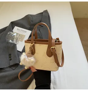 Detail van de crèmekleurige tote bag met vlinderreliëf en zachte pluche hanger