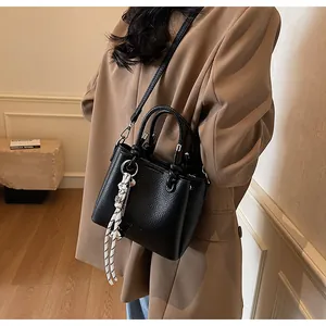 Sac seau élégant en cuir noir grainé porté en bandoulière pour un style chic et sobre
