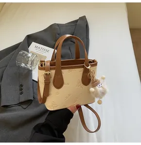 Beige and brown tote bag with butterfly embossing and a plush white charm
